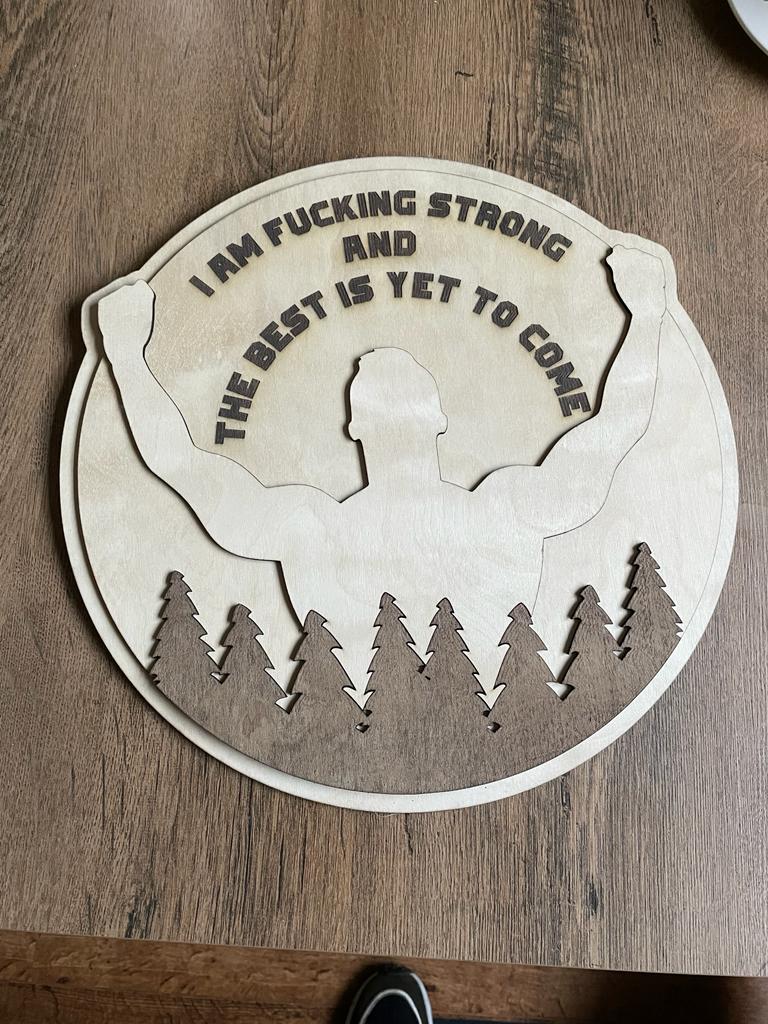 Houten plaque met de tekst "I AM FUCKING STRONG AND THE BEST IS YET TO COME" en silhouet.